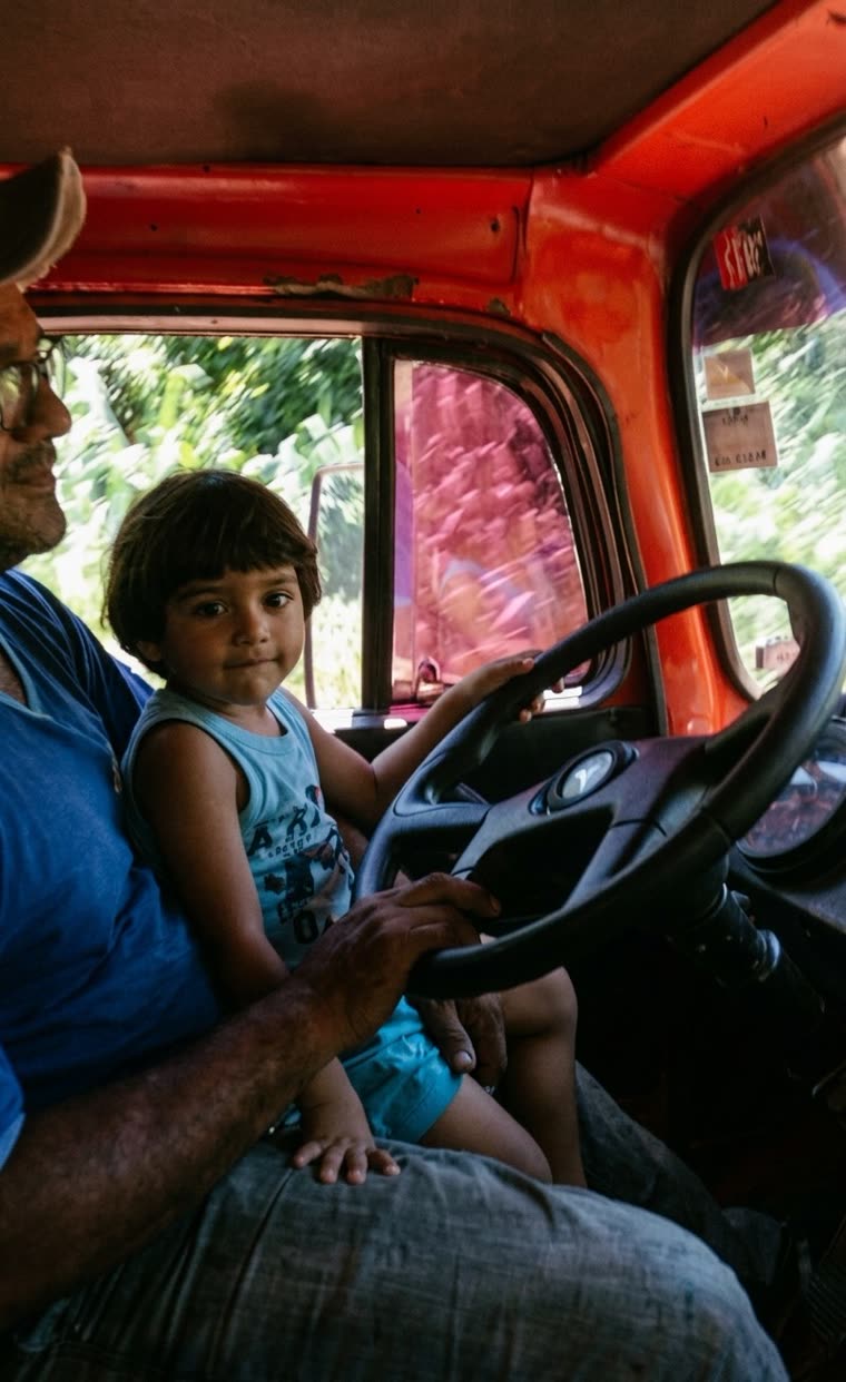 Criança sentada ao volante na cabine de um caminhão antigo